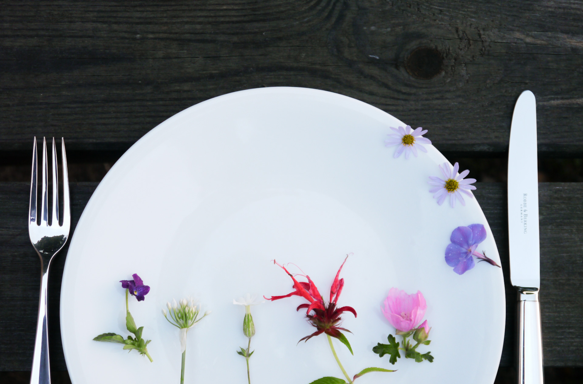 Messer, Gabel und Teller mit essbaren Blüten